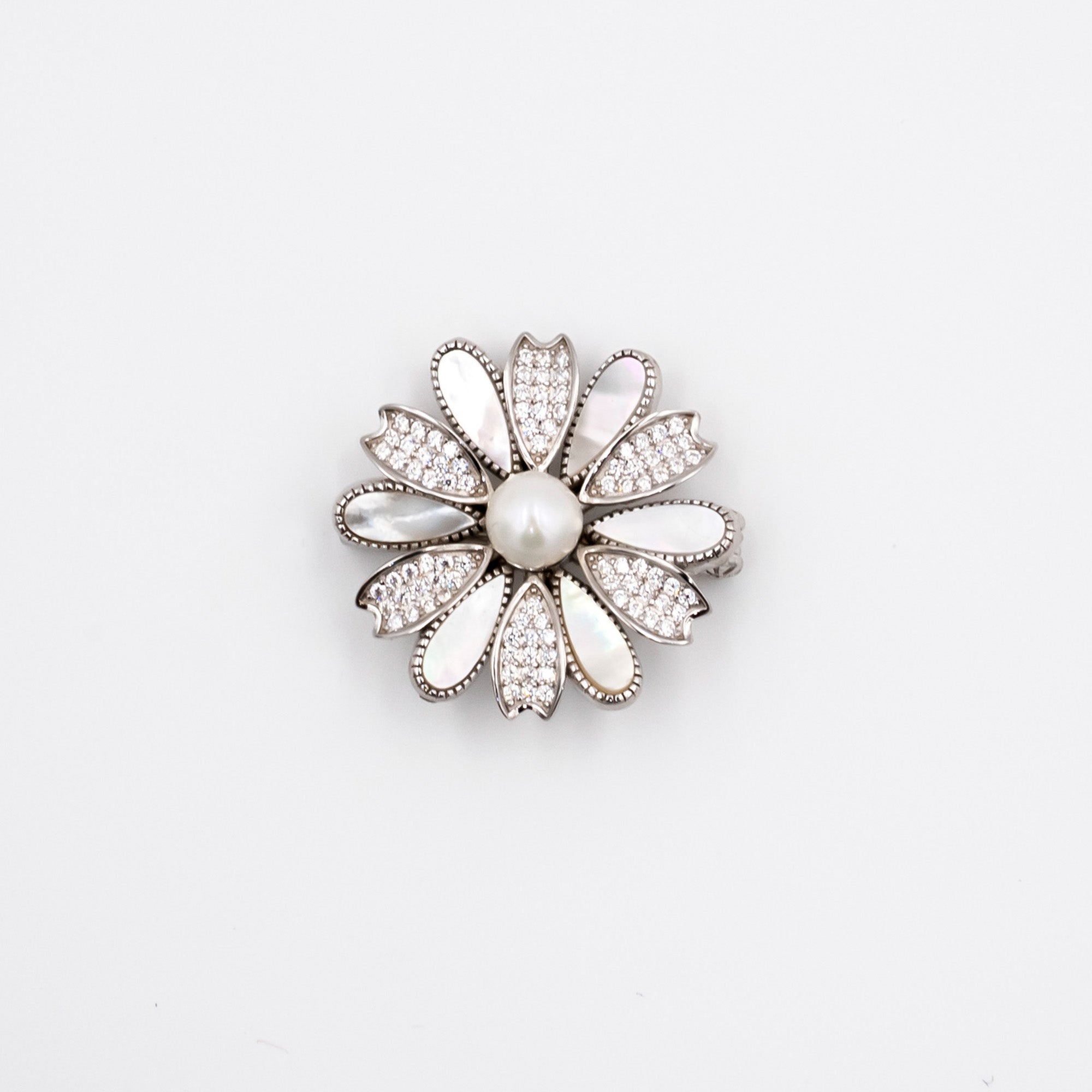 A silver-tone flower-shaped brooch featuring a central white pearl surrounded by clear rhinestones and white enamel petals, set against a plain white background.